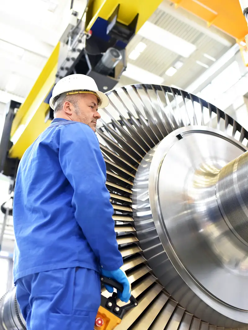 ouvrier se tenant debout près d'une partie d'un moteur d'avion